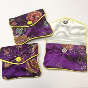 The front of three unique purple Floral Crystal Pouch