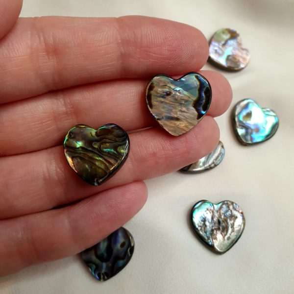 2 unique heart shaped abalone shell beads in my hand