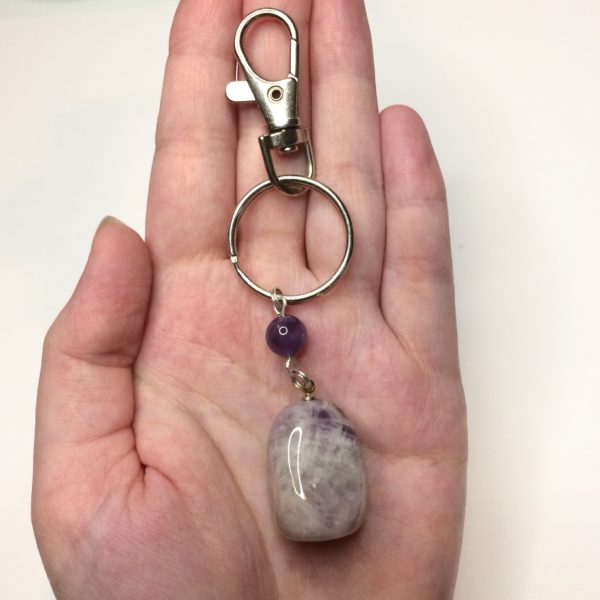 A woman's hand holding an Amethyst Pendant Keyring with an amethyst bead holding the pendant