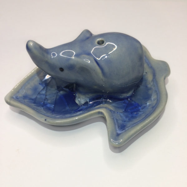 A blue elephant on a blue leaf, with a hole on the top of the elephant to hold an incense stick