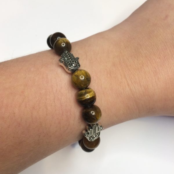 A woman wearing on her wrist a brown Tiger's Eye gemstone bead bracelets with five silver Hand of Fatima beads